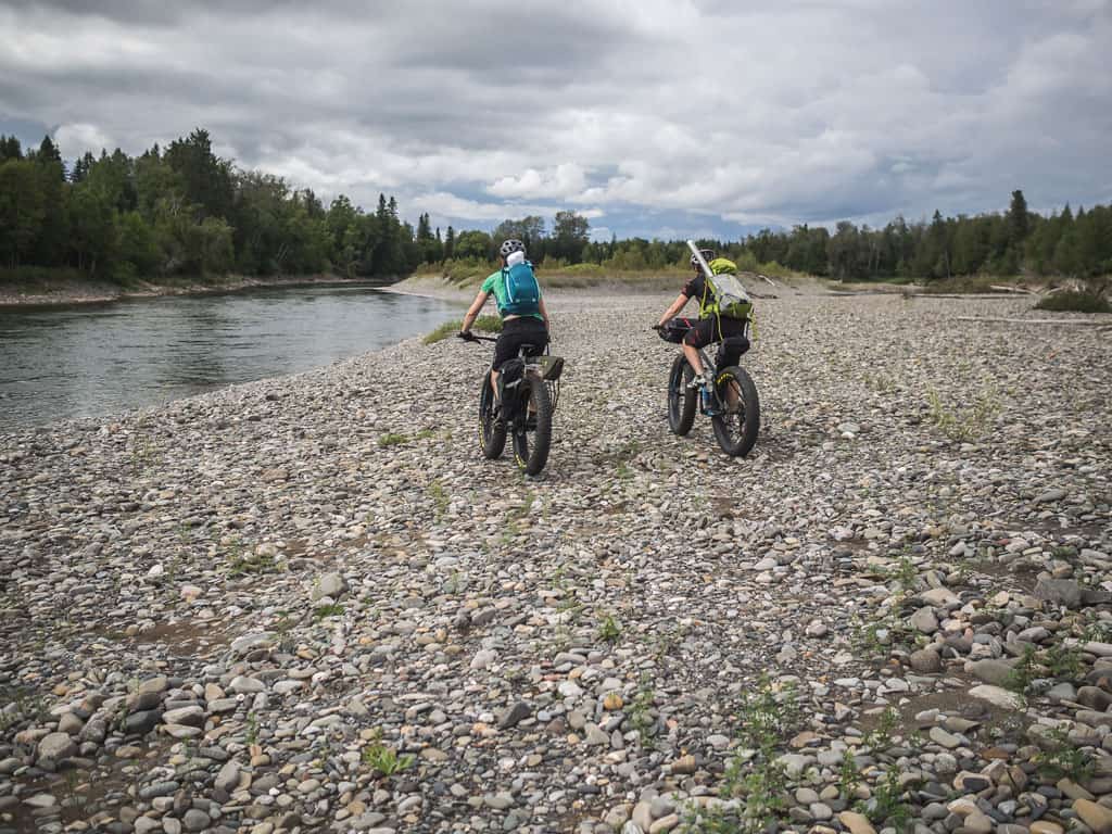 Deux filles sont en fatbike sur les berges de la rivière Bonaventure pour aller pêcher à la mouche