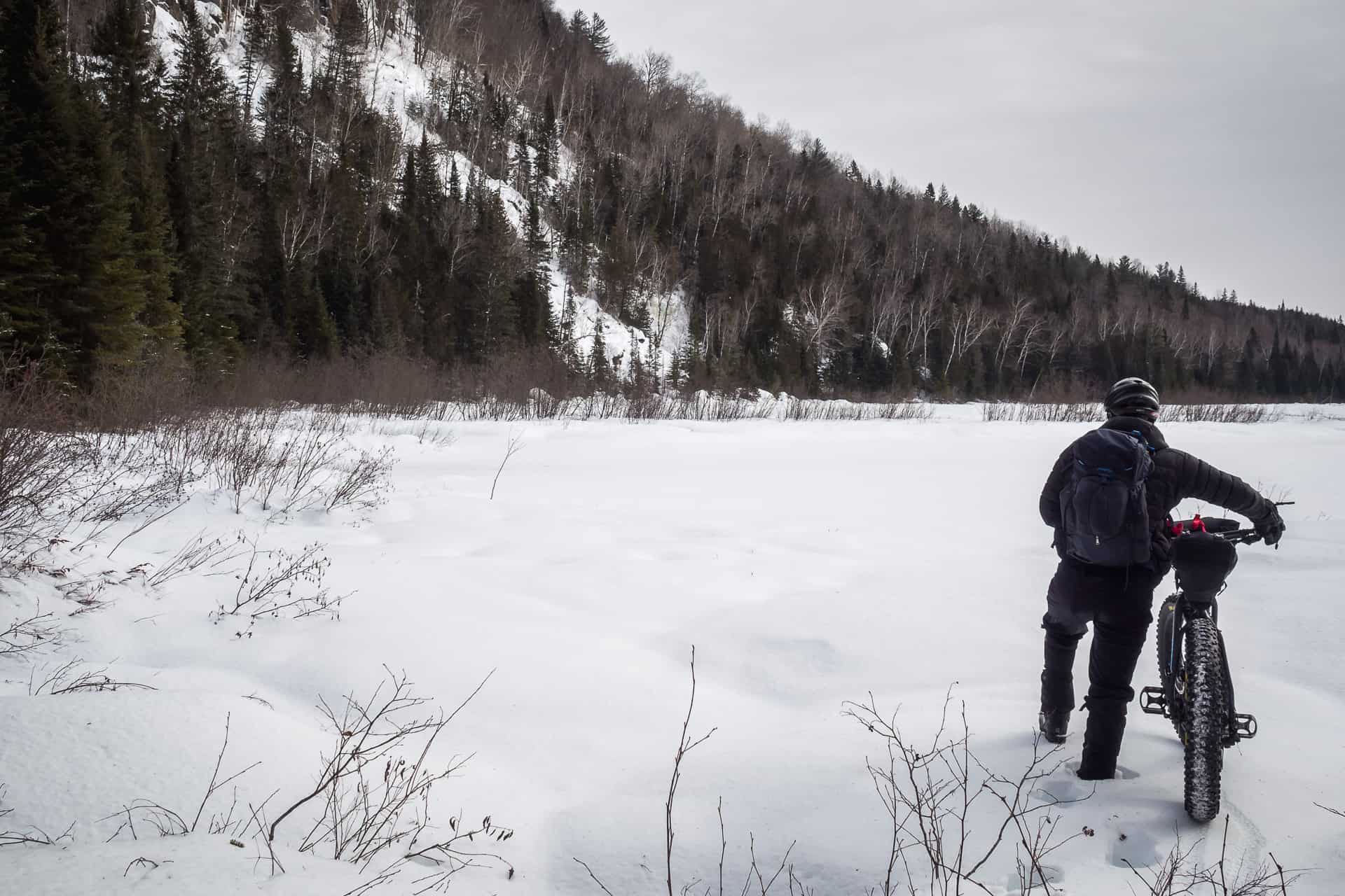 A man standing on the side of his fatbike on a frozen lake